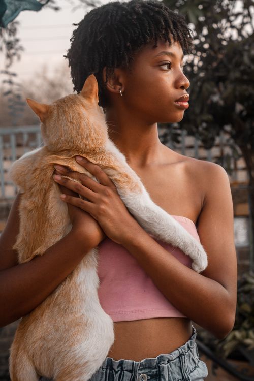 Free Portrait of a young woman outdoors holding a ginger cat in Mochudi, Botswana. Stock Photo