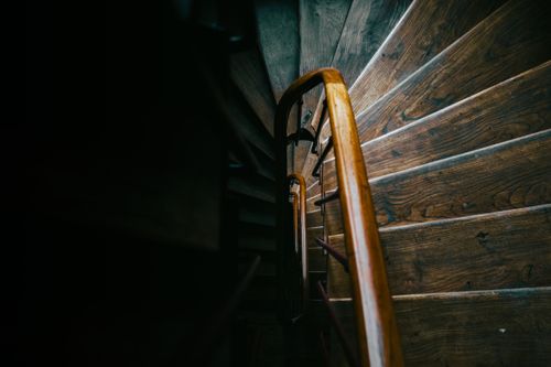 Free Artistic view of a spiral wooden staircase in Paris, capturing moody shadows and warm lighting. Stock Photo
