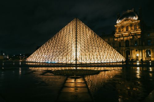 View of the Louvre Pyramid glowing at night, showcasing modern architecture in Paris, France.