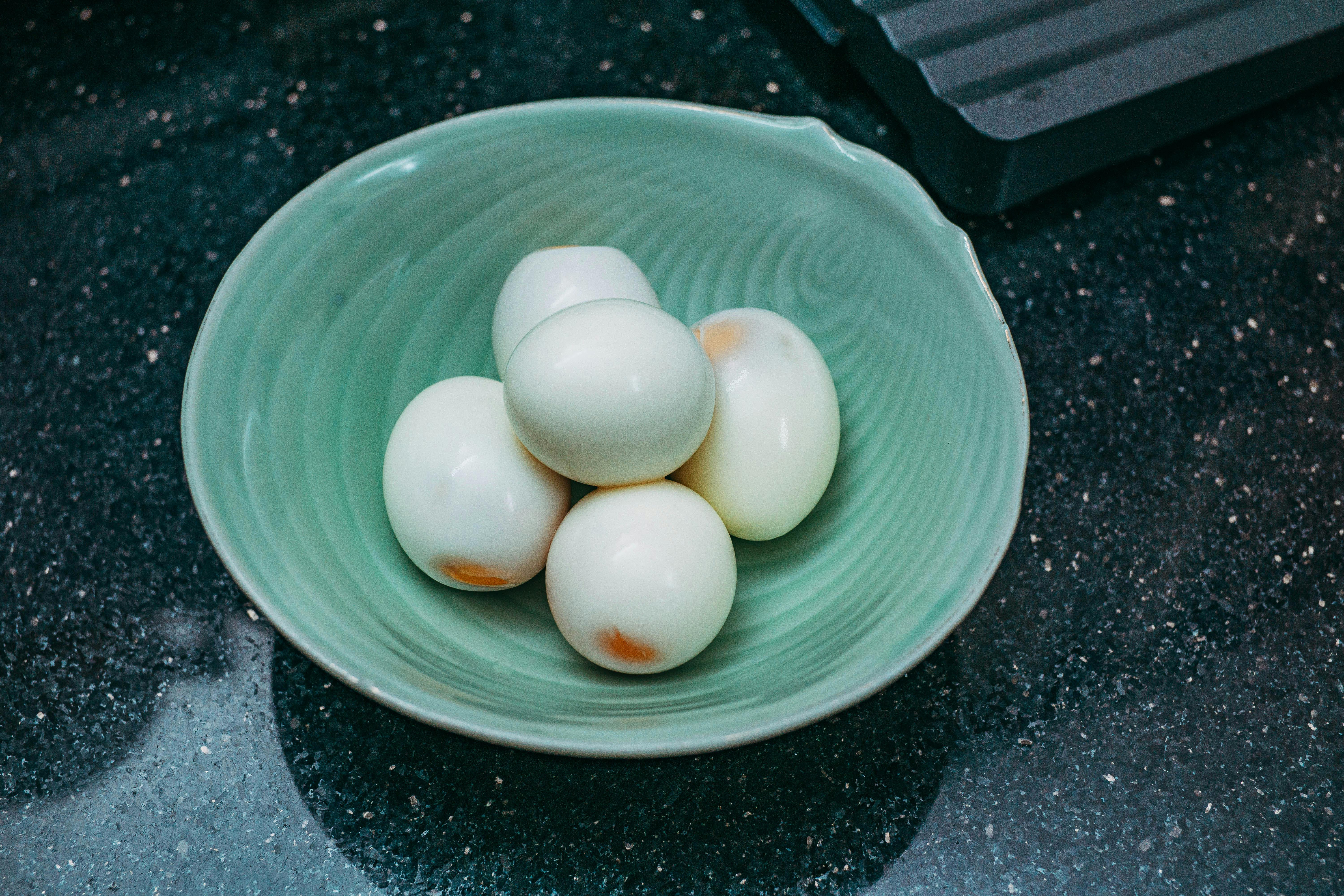 close up of boiled eggs in a green bowl