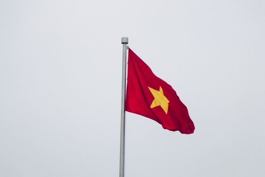 越南国旗在晴朗多云的天空中飘扬，生动地捕捉到了爱国主义与自由的象征