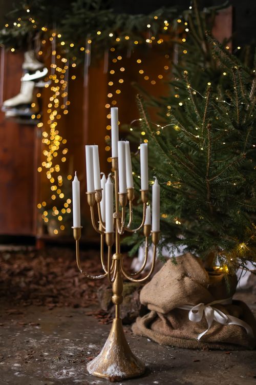 Free Gold candelabra with white candles and festive decor with fairy lights outdoors. Stock Photo
