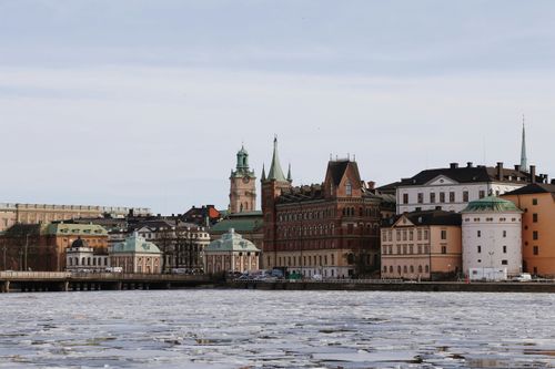Free Scenic winter view of historical buildings along Stockholm's waterfront with ice floating on the water. Stock Photo