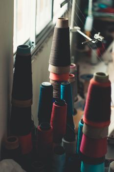 Colorful sewing threads stacked in an indoor workshop, ideal for textile art and craft projects.