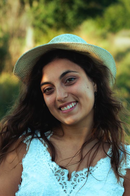 Free Joyful woman in a white dress and sun hat smiling outdoors in Argentina. Stock Photo