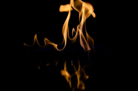 Vivid orange flames dancing on a black reflective surface, creating a dramatic visual scene.