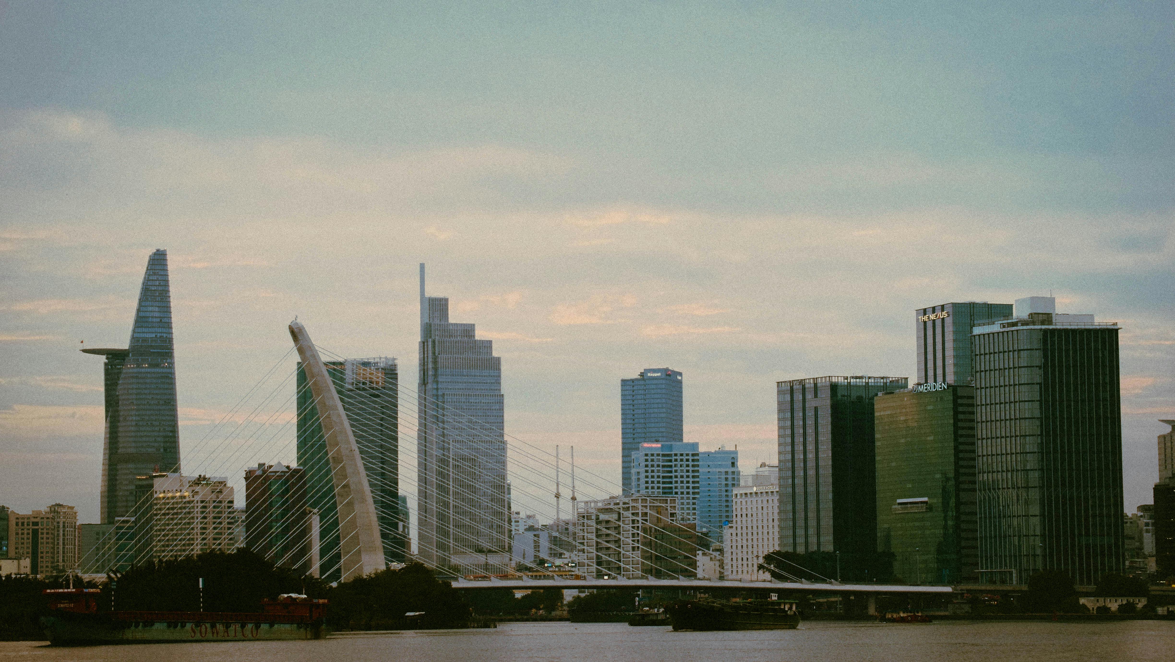 Scenic view of Hồ Chí Minh City skyline featuring iconic modern architecture and a serene river.