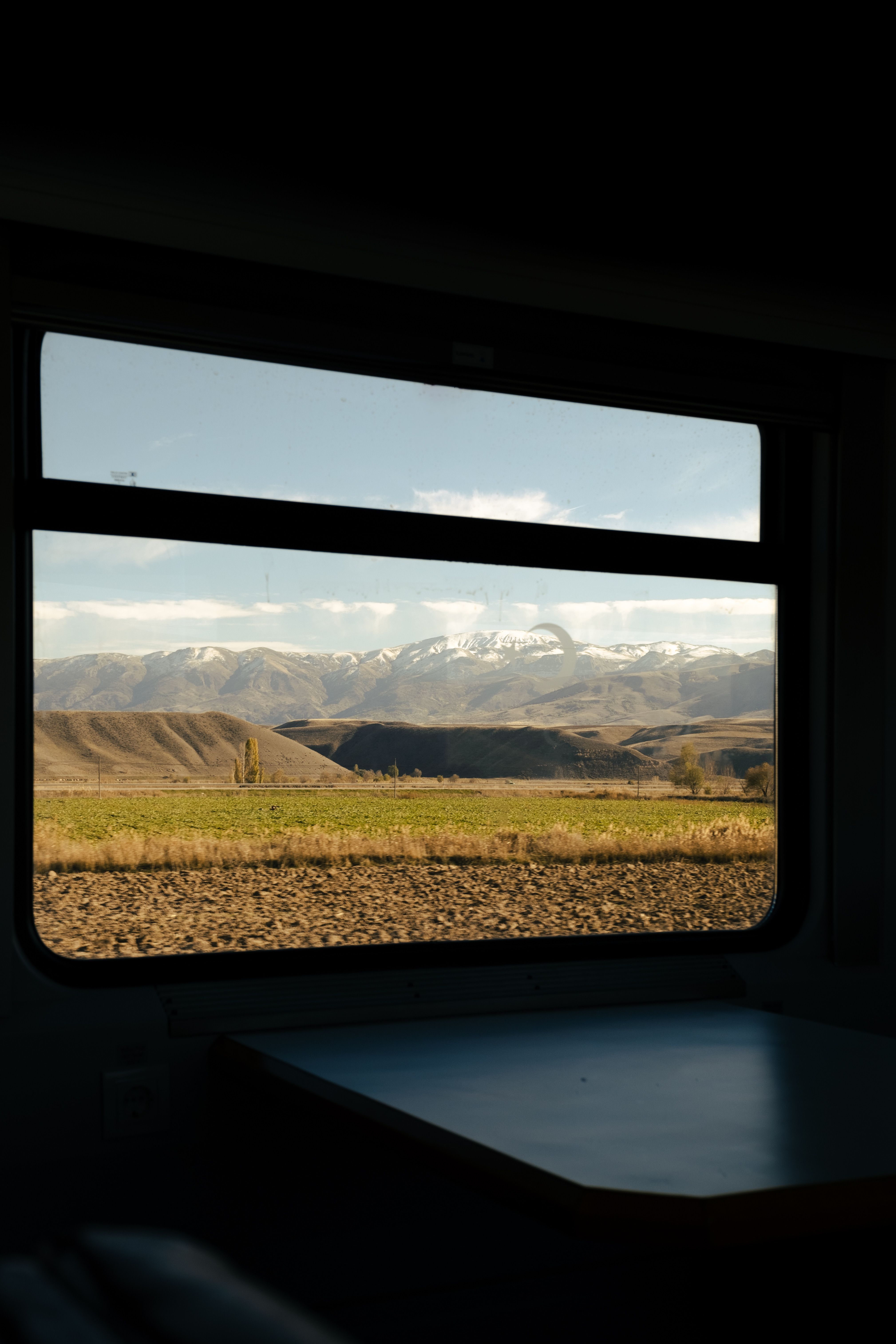 View of snow-capped mountains from a train window, capturing the serene landscape.
