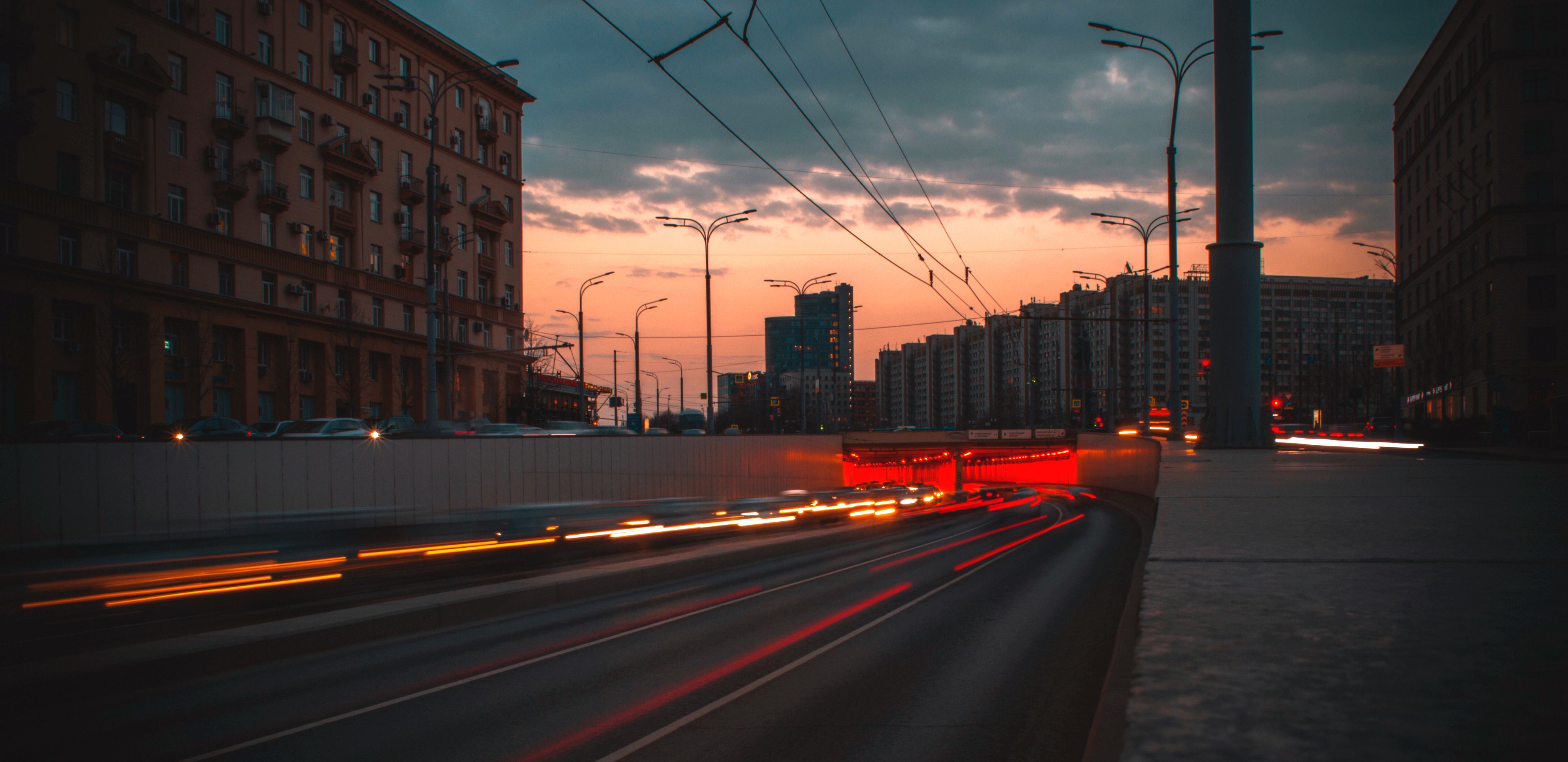 A red train on a track next to a city street · Free Stock Photo