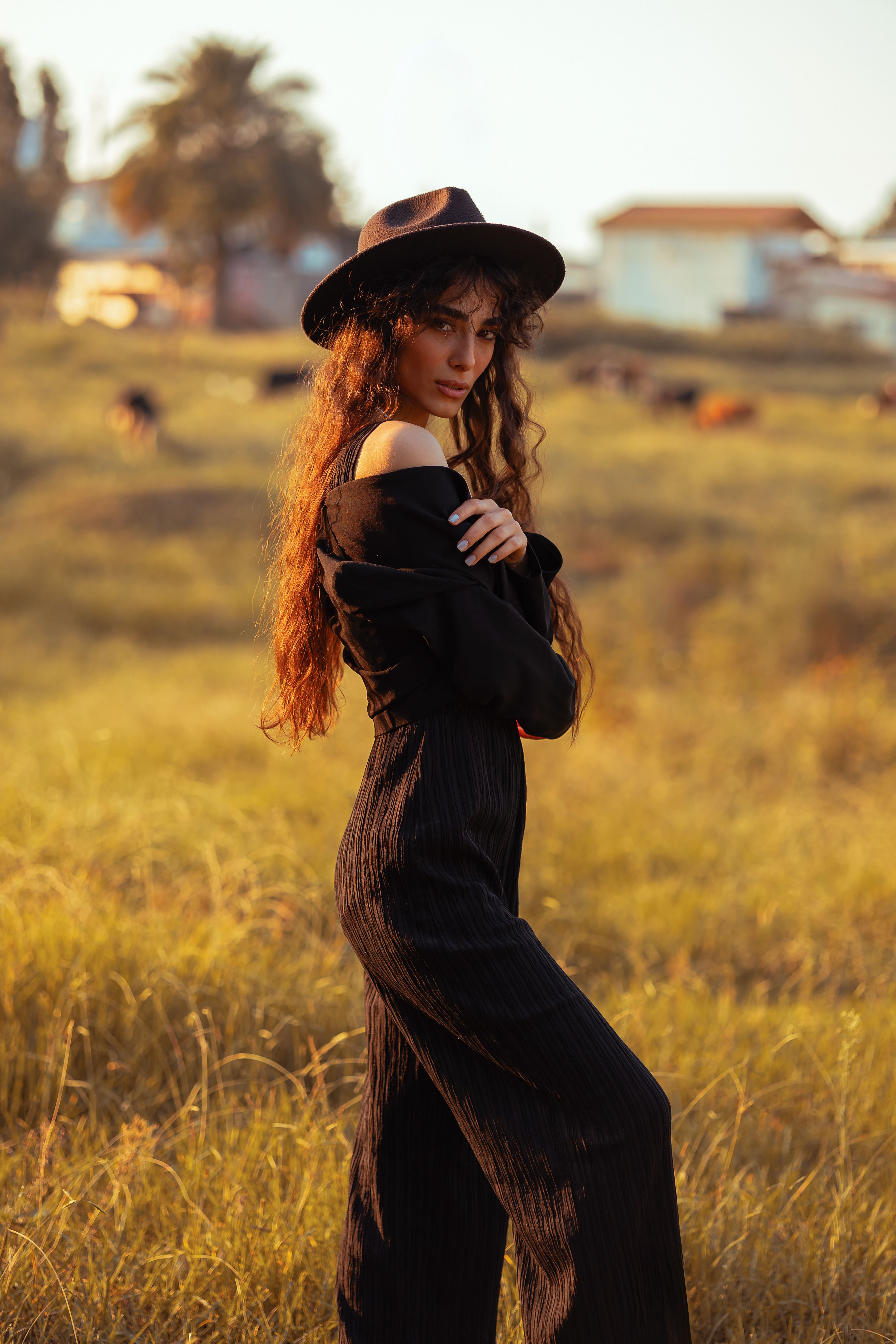 Stylish Woman in Black Hat in Sunlit Meadow · Free Stock Photo