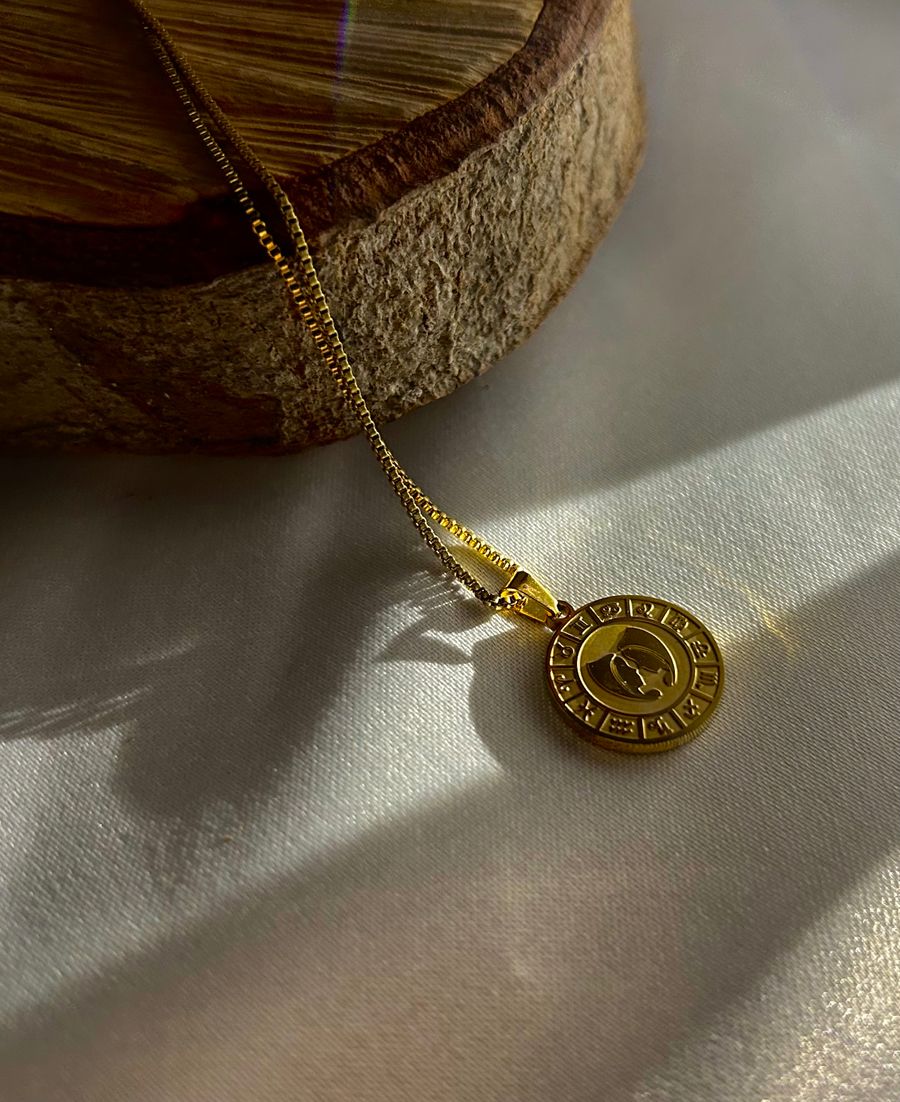 Gold pendant necklace on a wooden platform