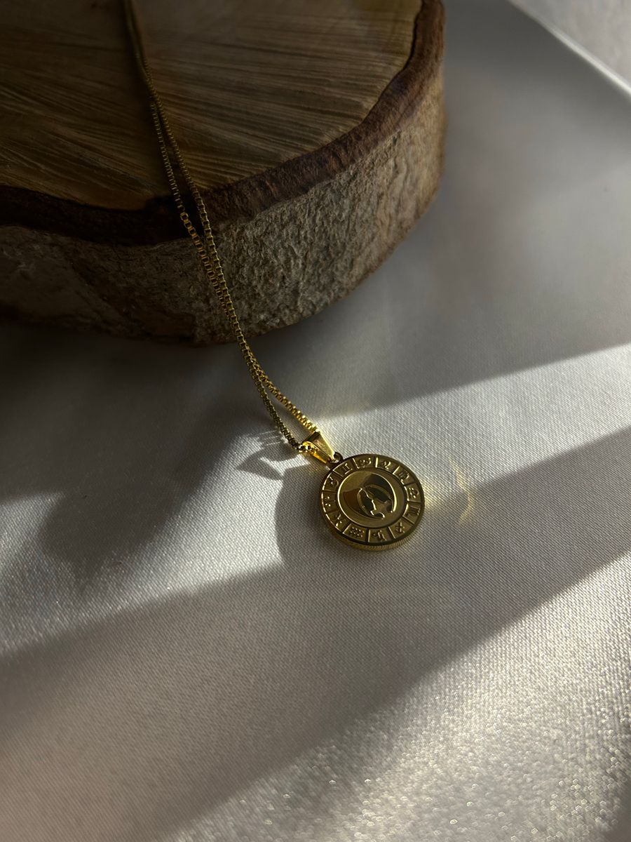 Gold necklace pendant on a wooden surface