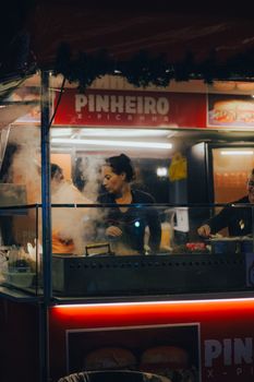 A busy food stall at night with vendors cooking and serving delicious meals.