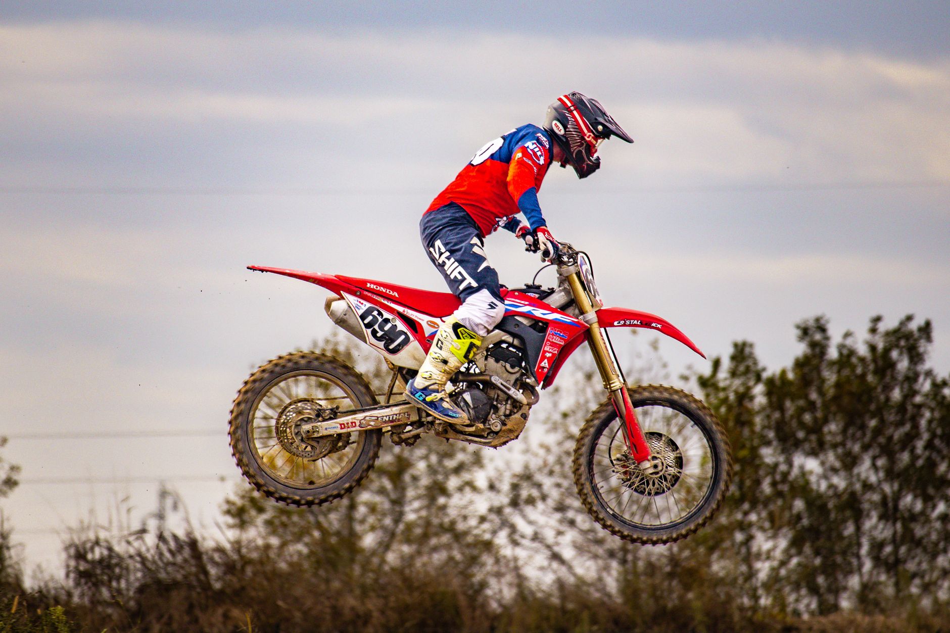 Motocross rider performs an impressive jump during an outdoor event.