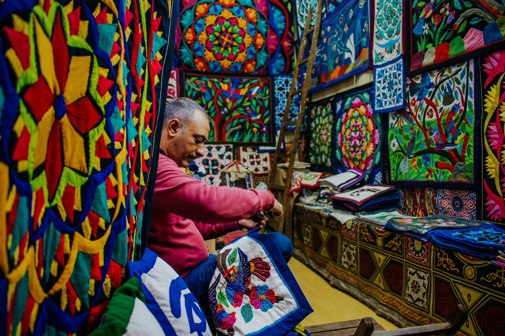 Vibrant textile shop with craftsman showcasing colorful intricate textiles and patterns.