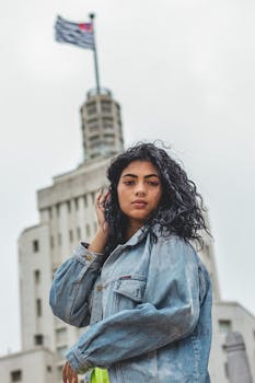 一名女子身穿牛仔夹克，在一座历史悠久的建筑前摆姿势