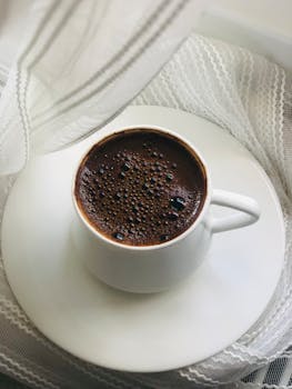 A steaming cup of coffee on a lacy surface, creating a cozy and inviting mood.