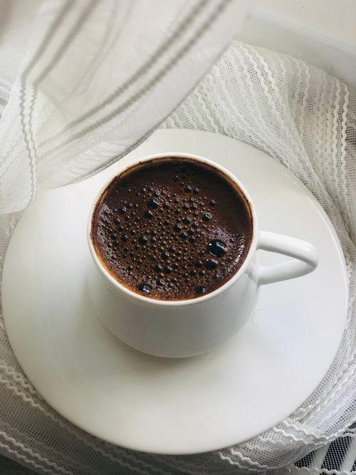 Free A steaming cup of coffee on a lacy surface, creating a cozy and inviting mood. Stock Photo