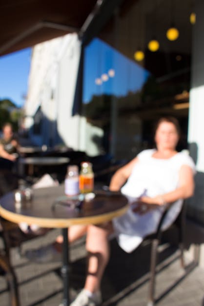 Free stock photo of blurred image, drinking juice outside siting on a chair, eating outside