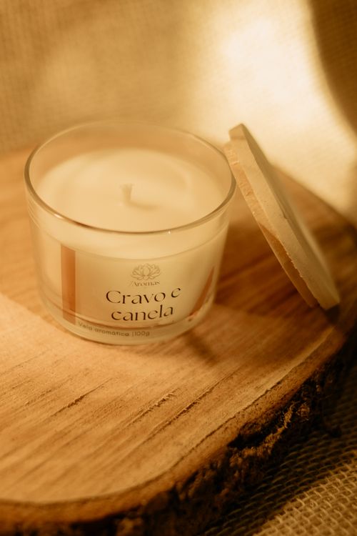 Free Cozy clove and cinnamon scented candle in soft warm lighting on wood. Stock Photo