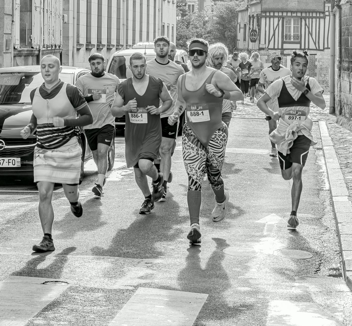 Participants in a fun run wearing various costumes on a city street. Energetic race scene.