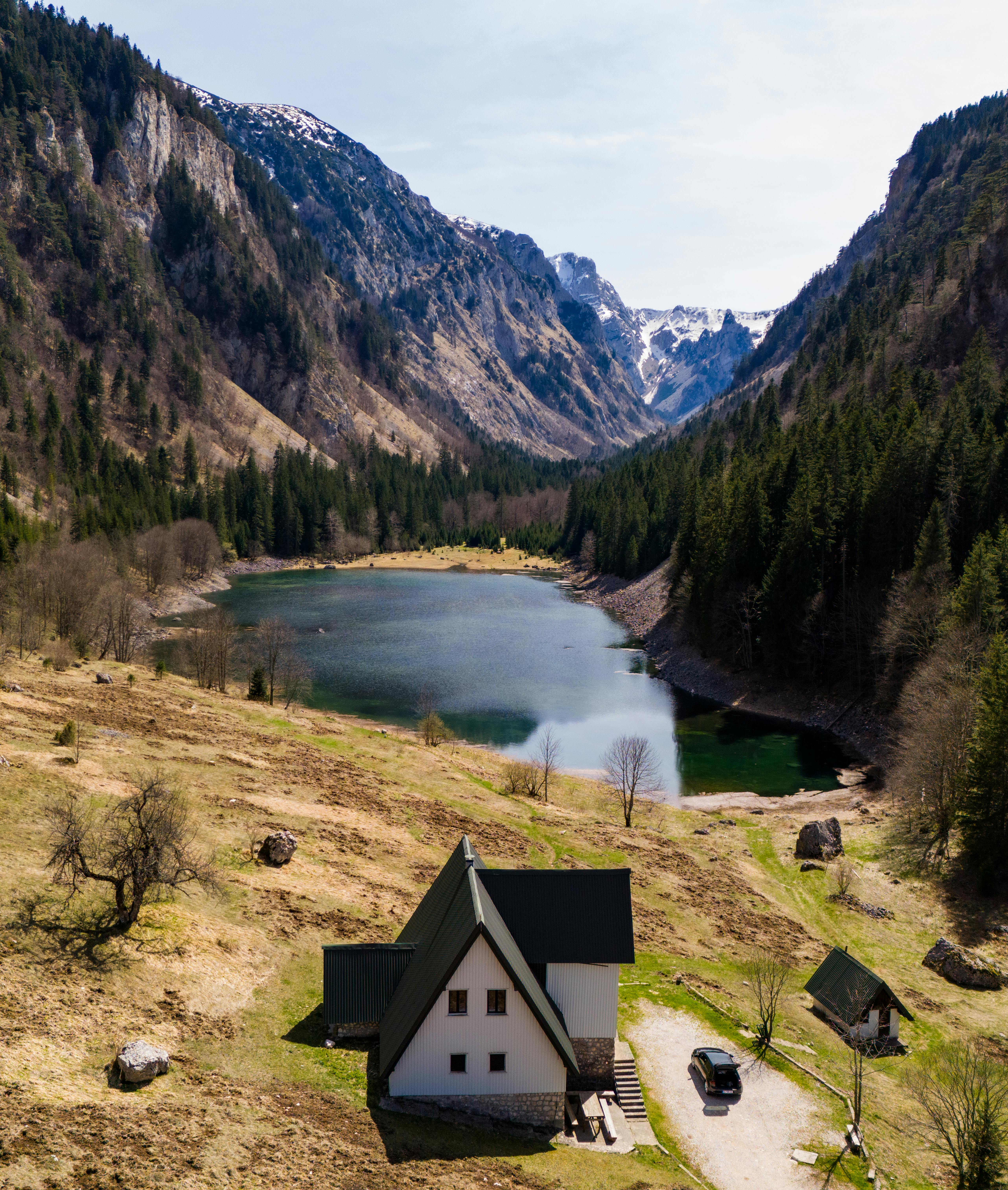 A serene lake surrounded by mountains and a cozy house in Montenegro's wilderness.