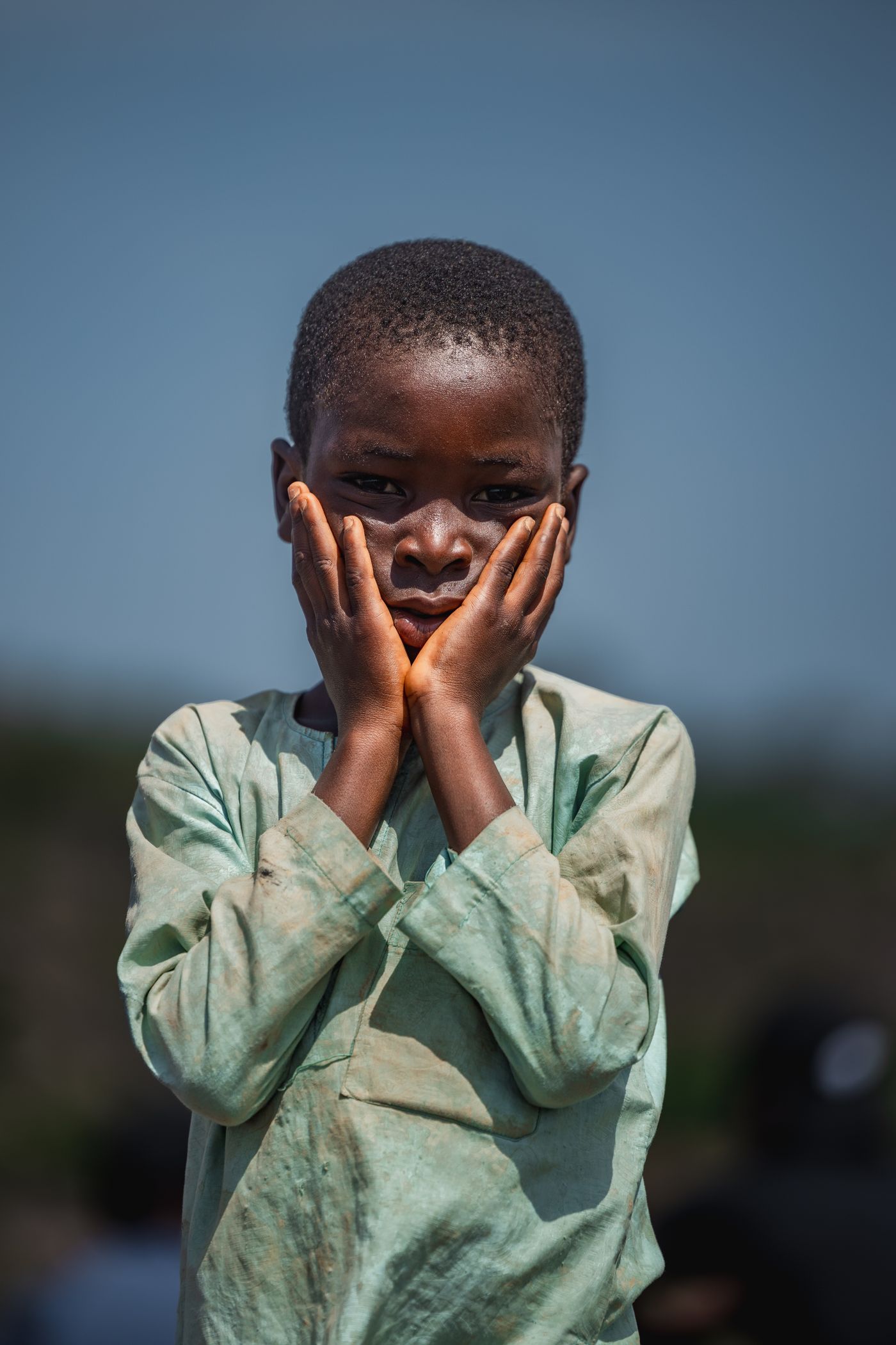 A young child in a pale tunic, photographed outdoors in even light.