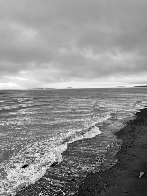 Free Black and white ocean scene with dramatic clouds and waves at twilight. Stock Photo