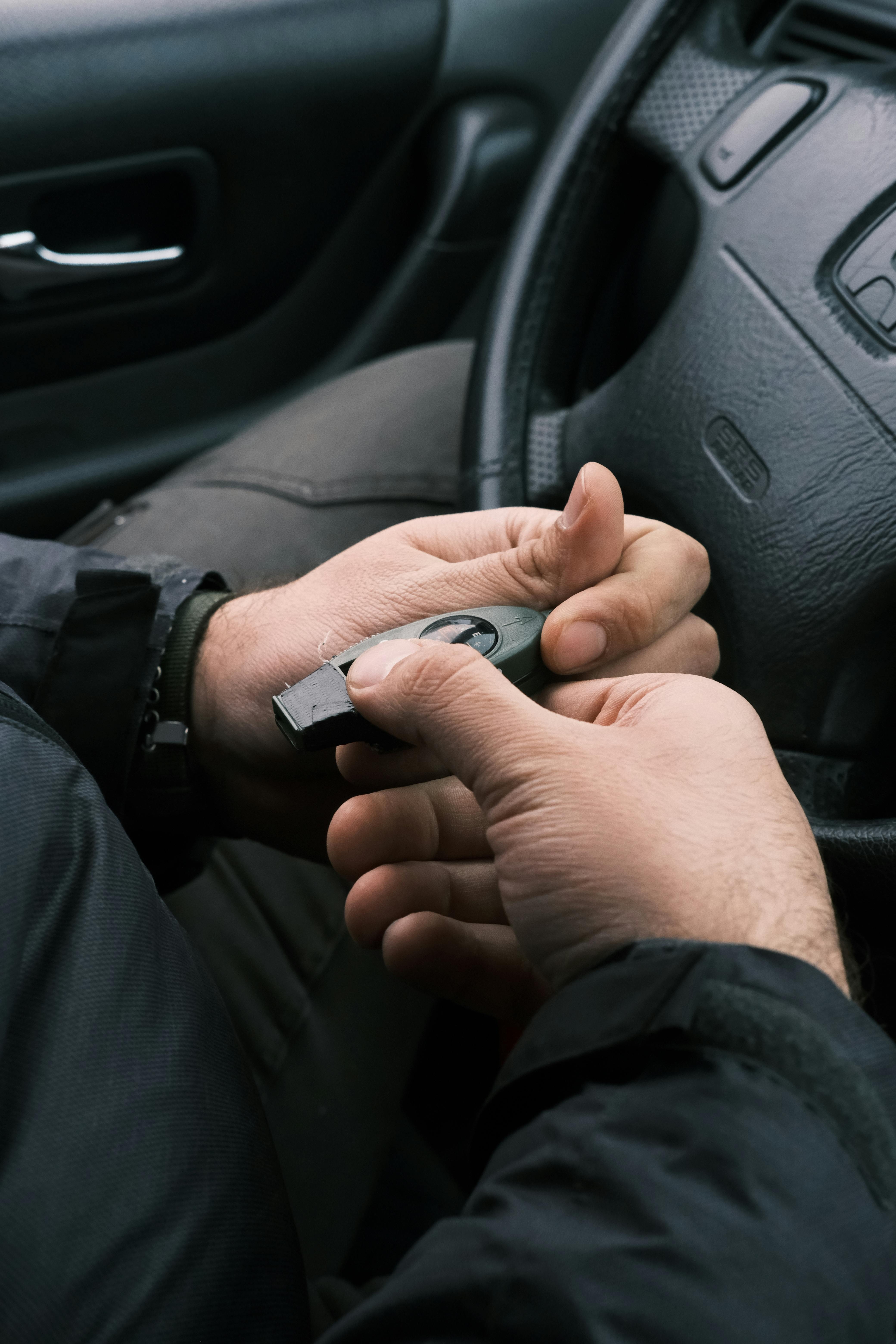 A close-up of a man's hands holding a compass inside a car.