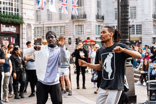 Free Energetic dancers perform in Piccadilly Circus, London, entertaining a diverse crowd. Stock Photo