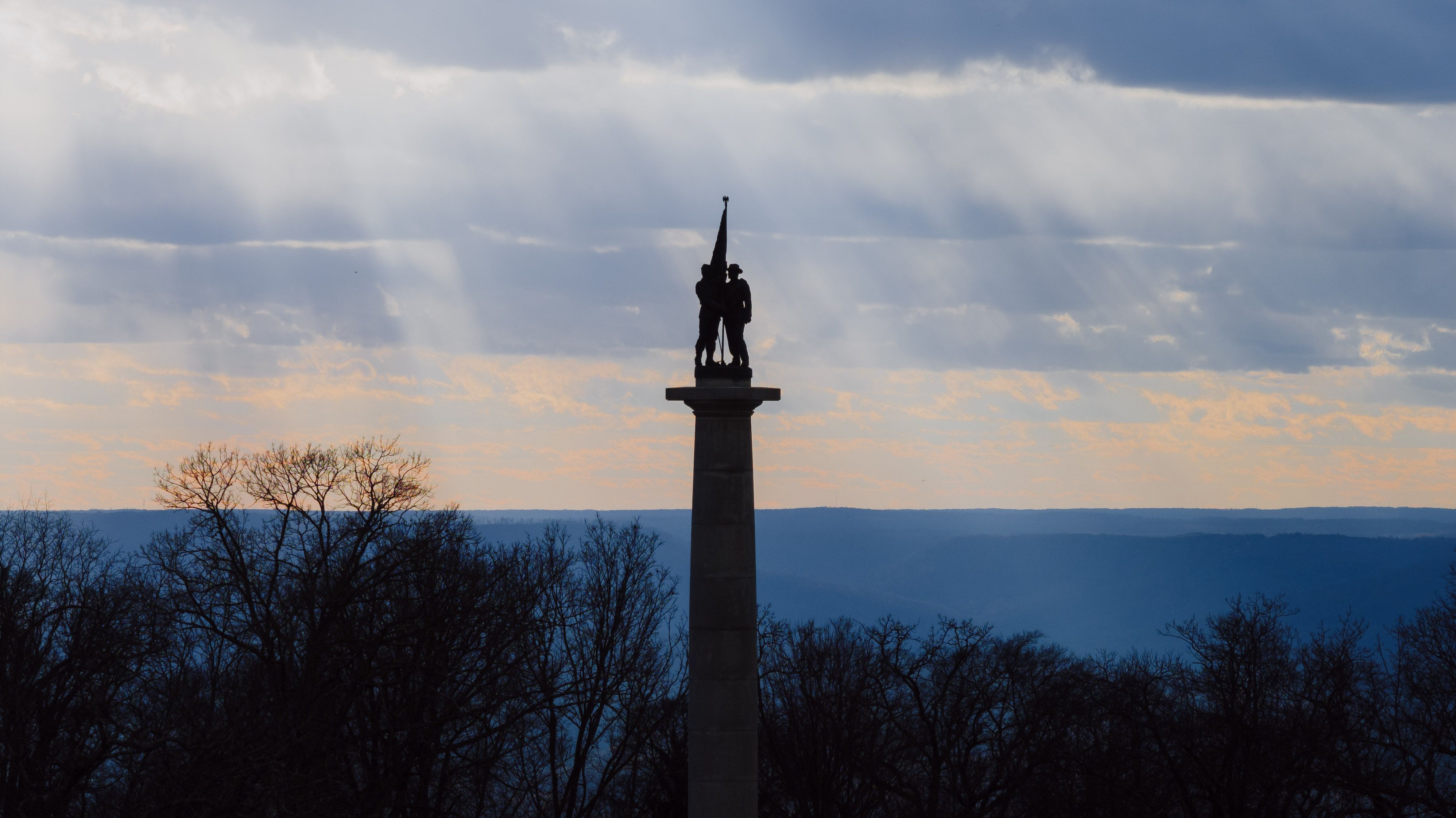A memorial monument silhouetted against a sunset sky