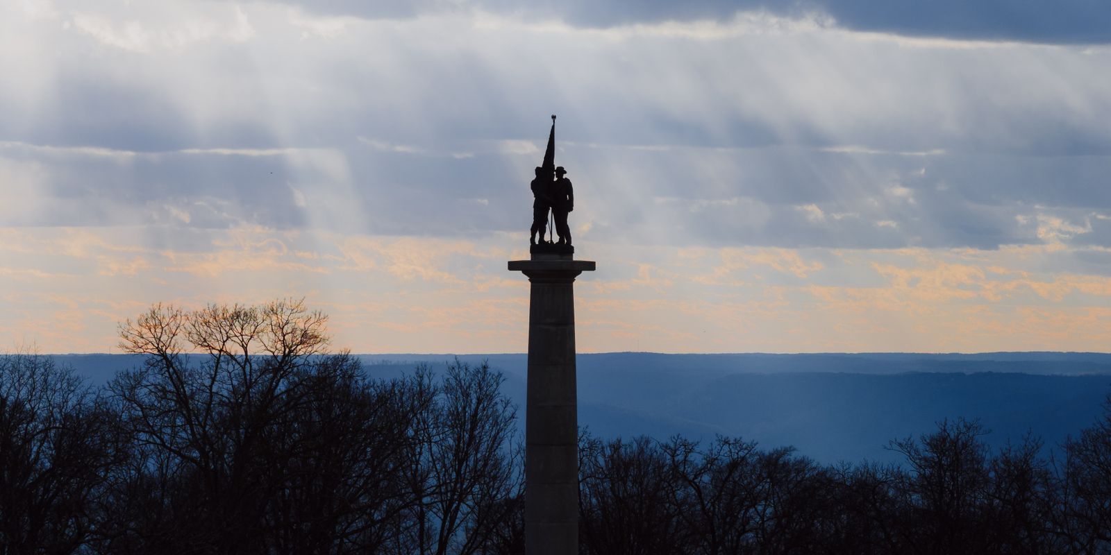 A memorial monument silhouetted against a sunset sky