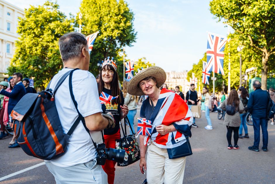 Joyful street scene in Central London with people celebrating under Union Jack flags, capturing vibrant city life.