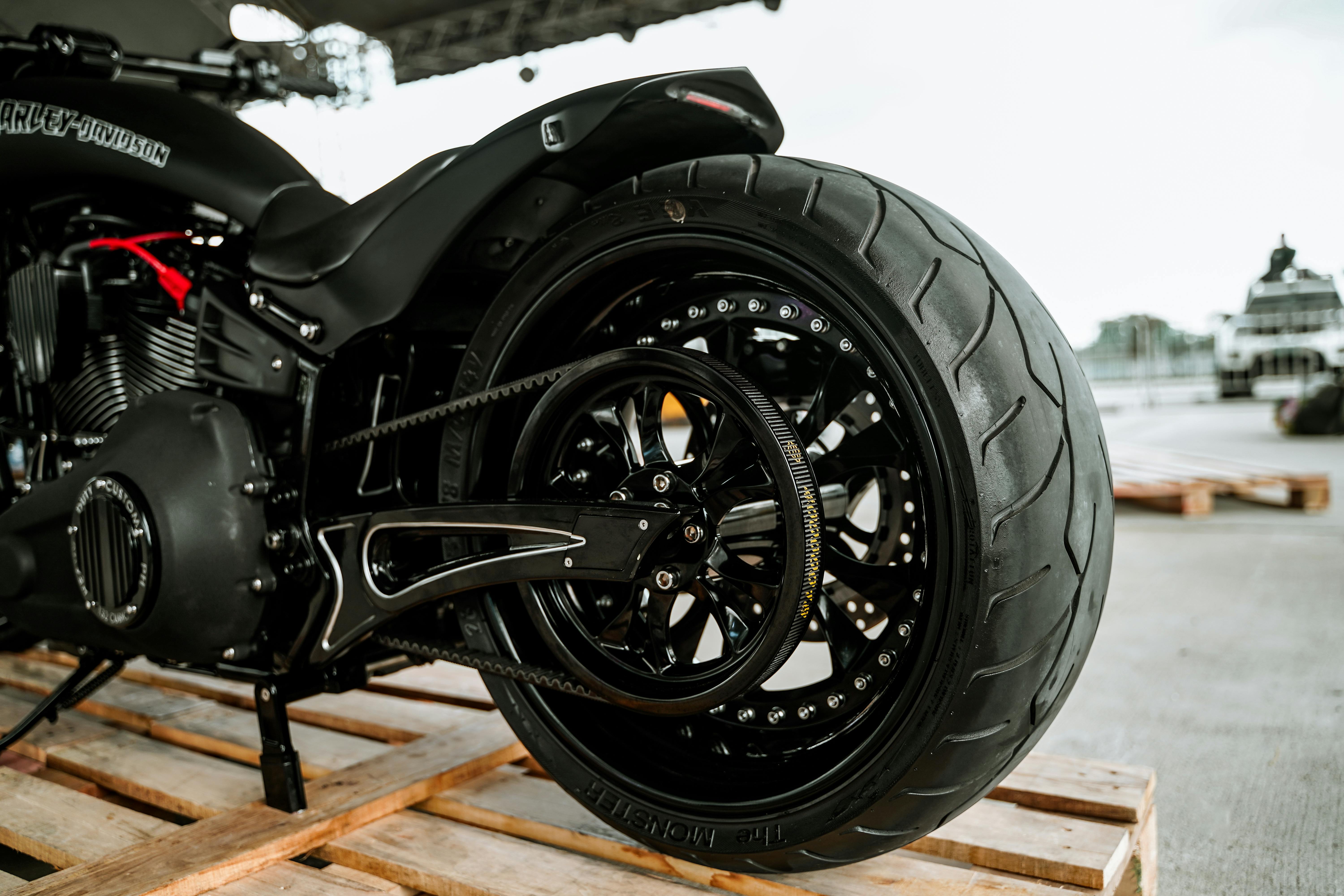 Detailed view of a Harley-Davidson motorcycle wheel on a wooden platform in an outdoor setting.