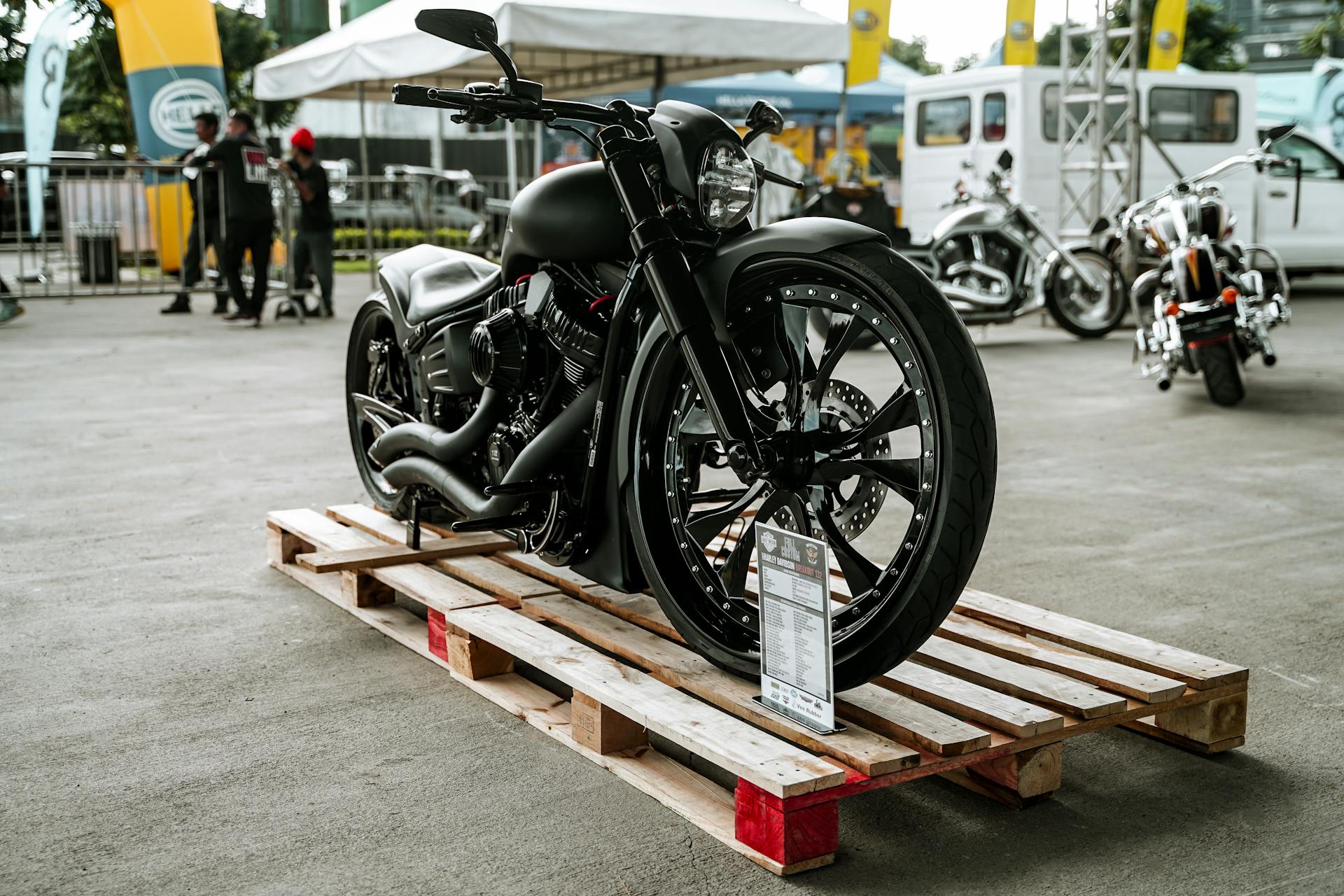 A stylish black motorcycle showcased on a wooden pallet in an outdoor event in Quezon City, Philippines.