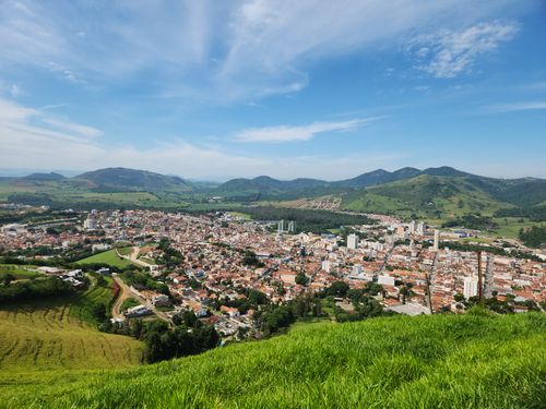 Free Aerial view of a scenic town nestled among lush green hills under a clear blue sky. Stock Photo