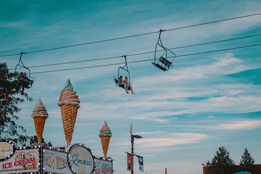View of people on cable cars above colorful festival scenery with ice cream decorations.