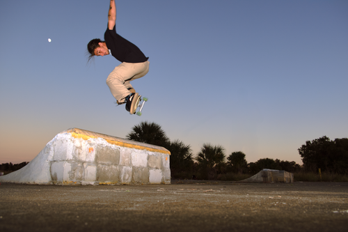 Free Dynamic skateboard trick captured at dusk in an outdoor skatepark setting. Stock Photo