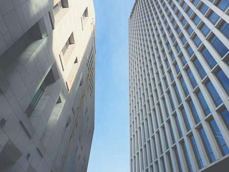 Upward view of modern skyscrapers with clear blue sky, architectural symmetry