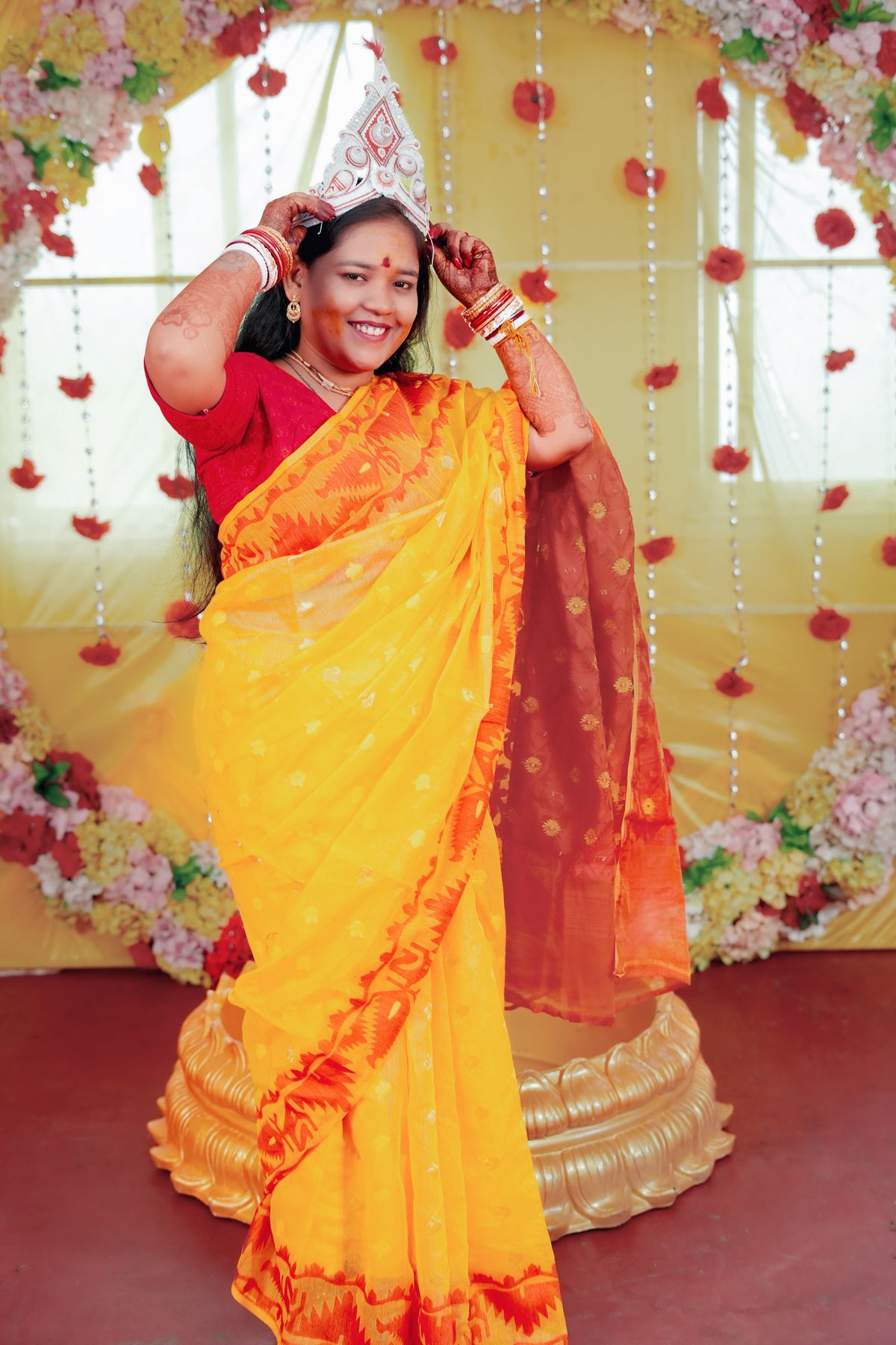 Woman in a bright yellow saree with a red border at a festive celebration