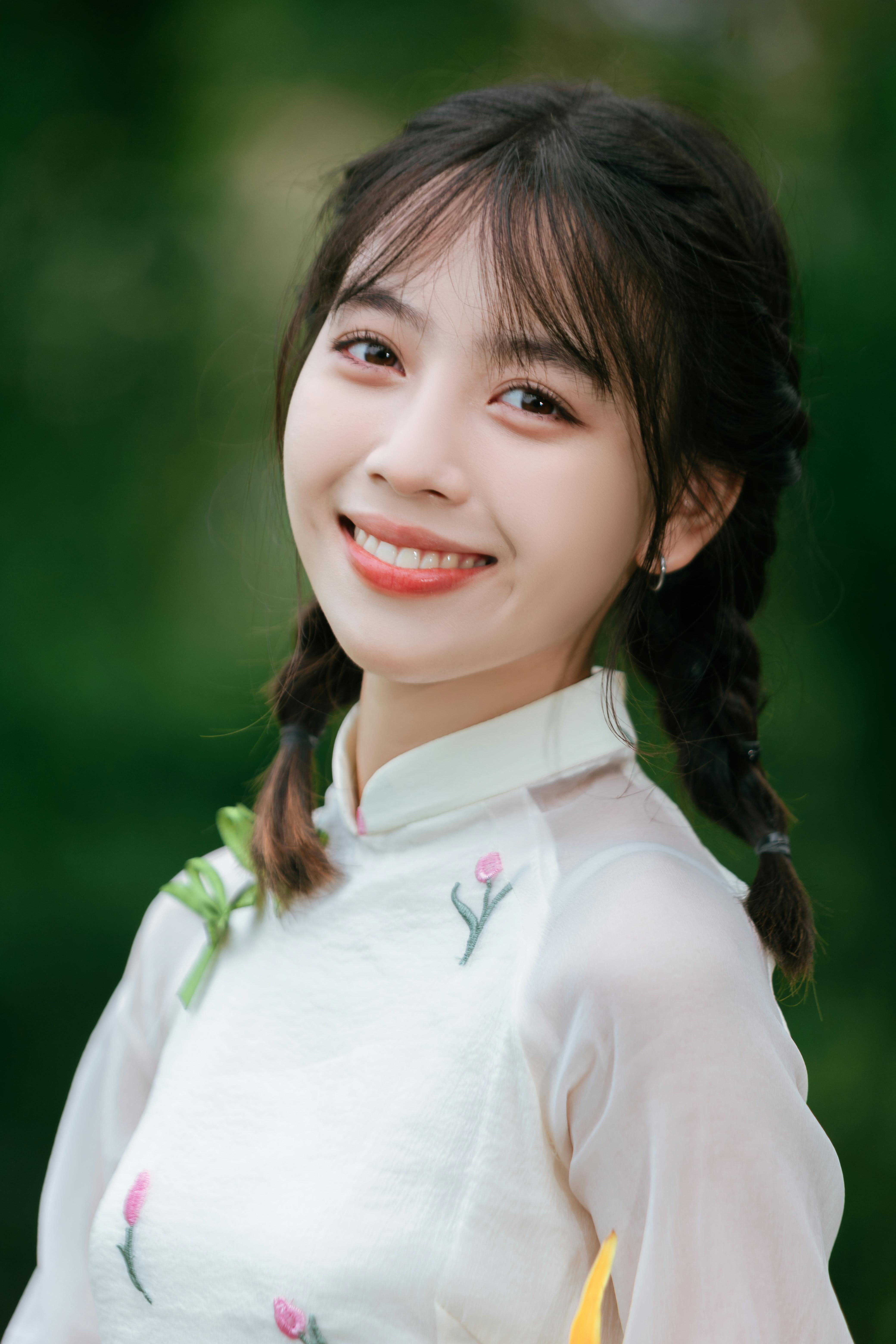 A cheerful woman in traditional attire smiles warmly outdoors.