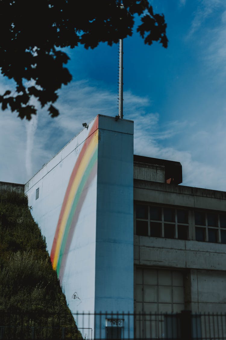 Perspective Of A White Concrete Building With A Rainbow Mural On The Side Wall