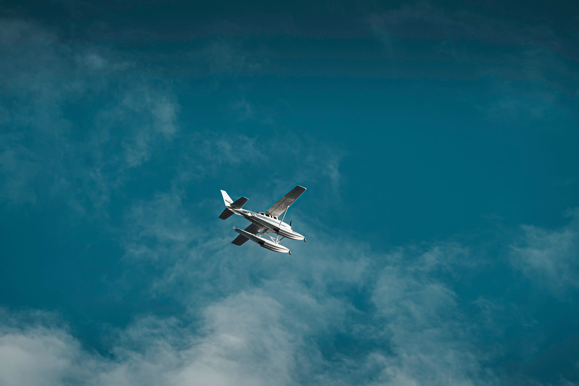 A captivating view of a seaplane flying against a vibrant blue sky and cloudscape.