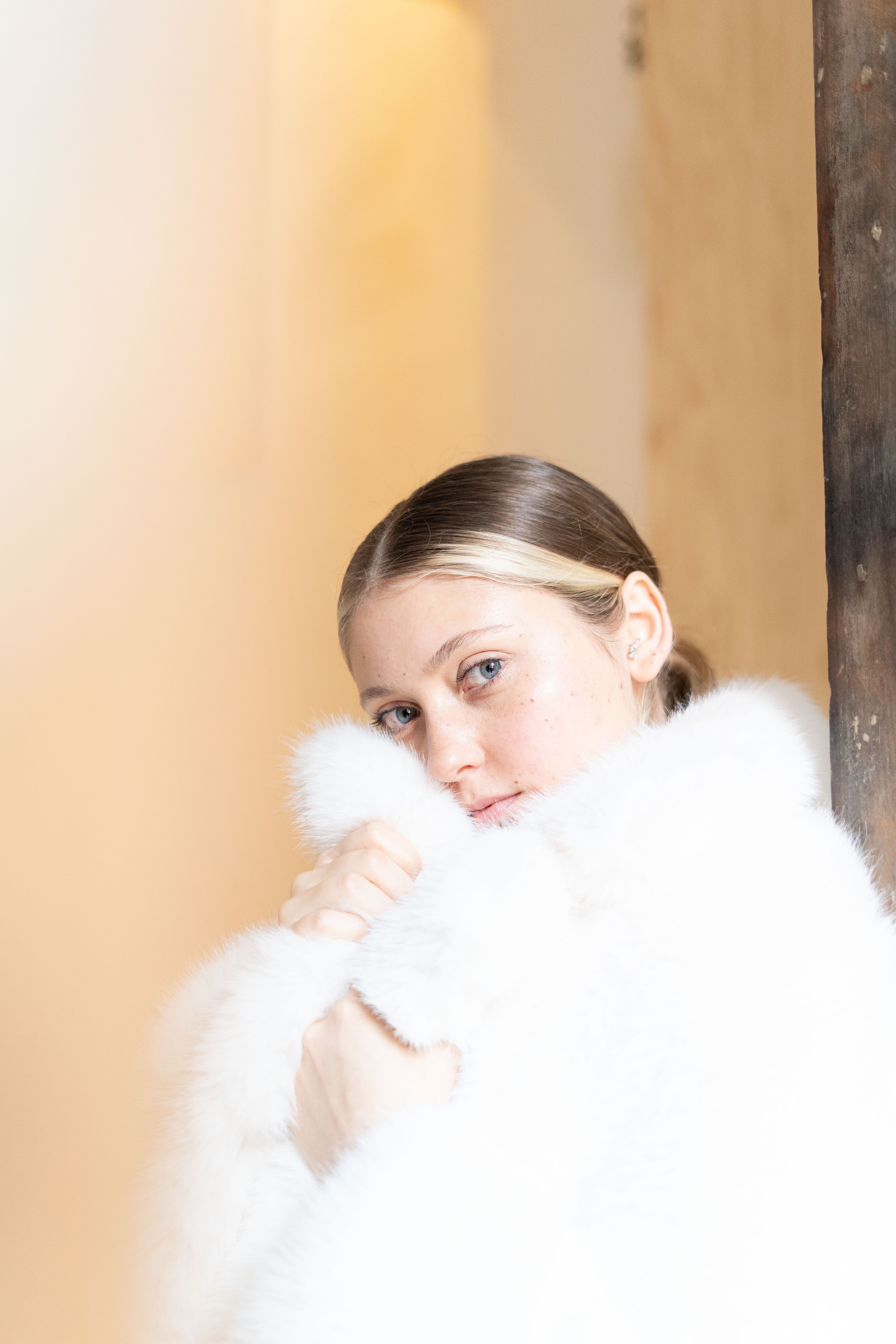 Gratuit Une femme regardant doucement tout en étant enveloppée dans un luxueux manteau de fourrure blanche. Photos