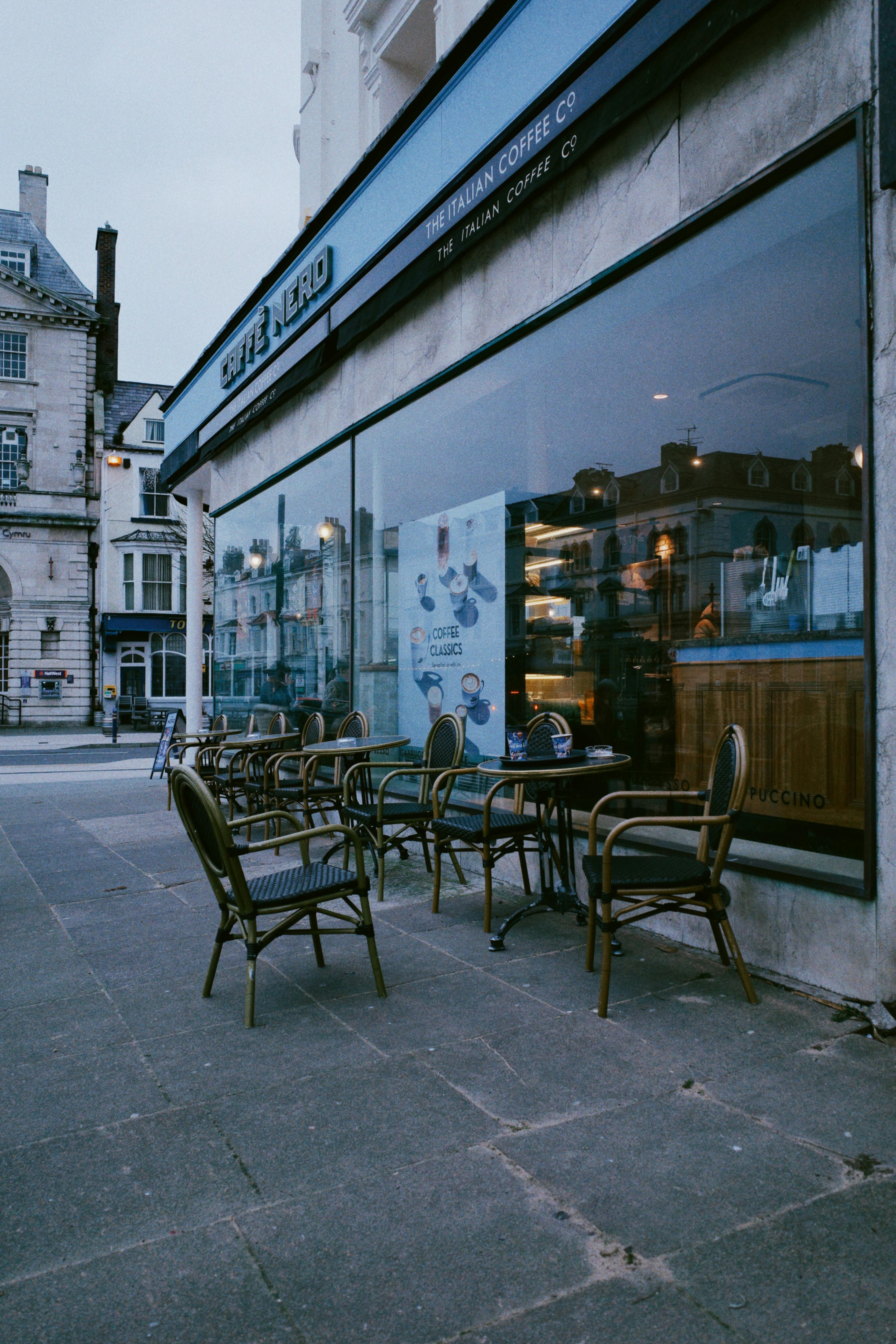 Cozy outdoor seating at a European cafe with a vintage charm and city backdrop.