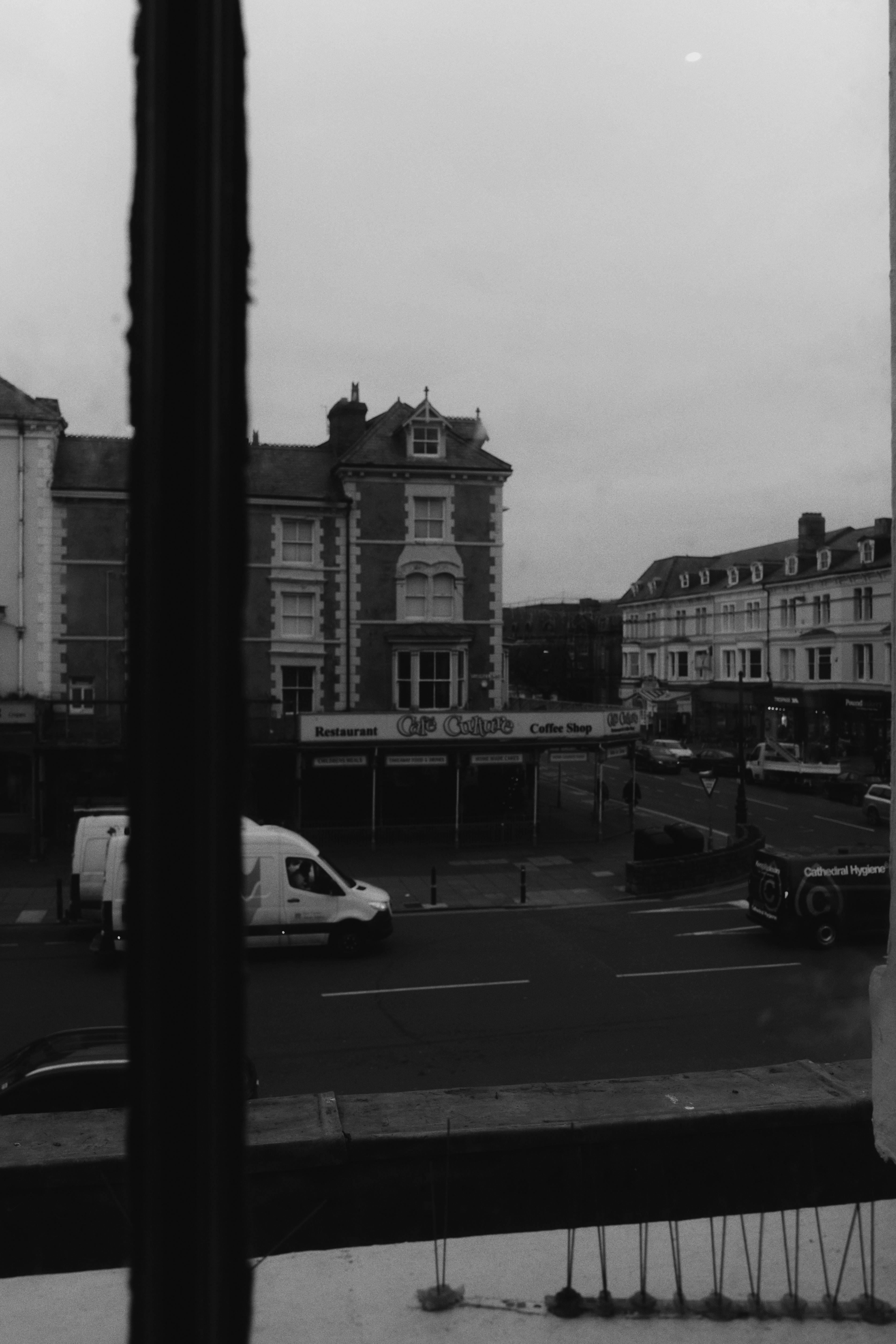 Monochrome view of a vintage urban street scene captured from a window.