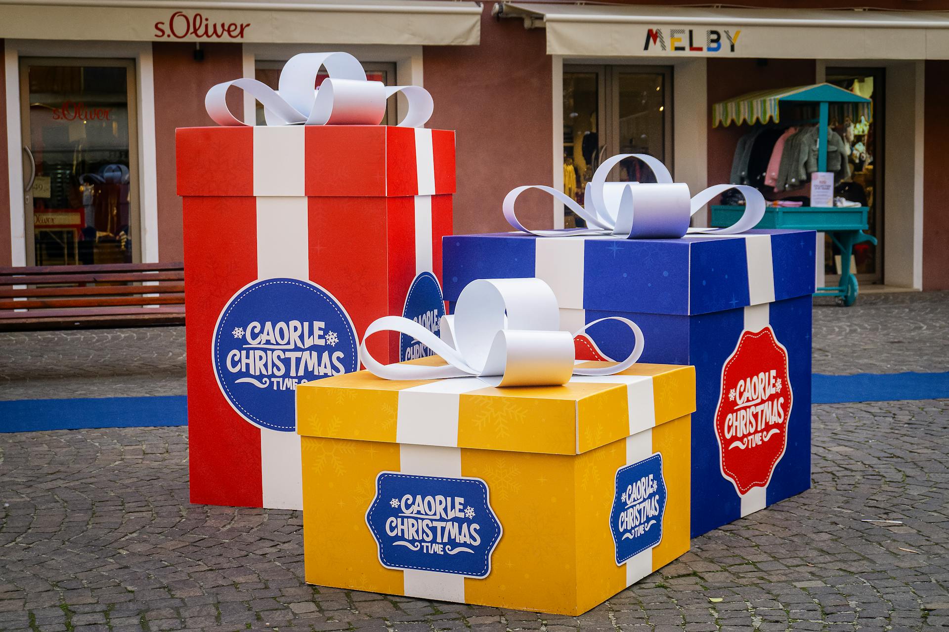 Vibrant oversized gift boxes in an outdoor shopping area, perfect for holiday themes.