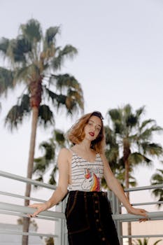 日落时分，一位时尚的年轻女子在棕榈树旁摆姿势