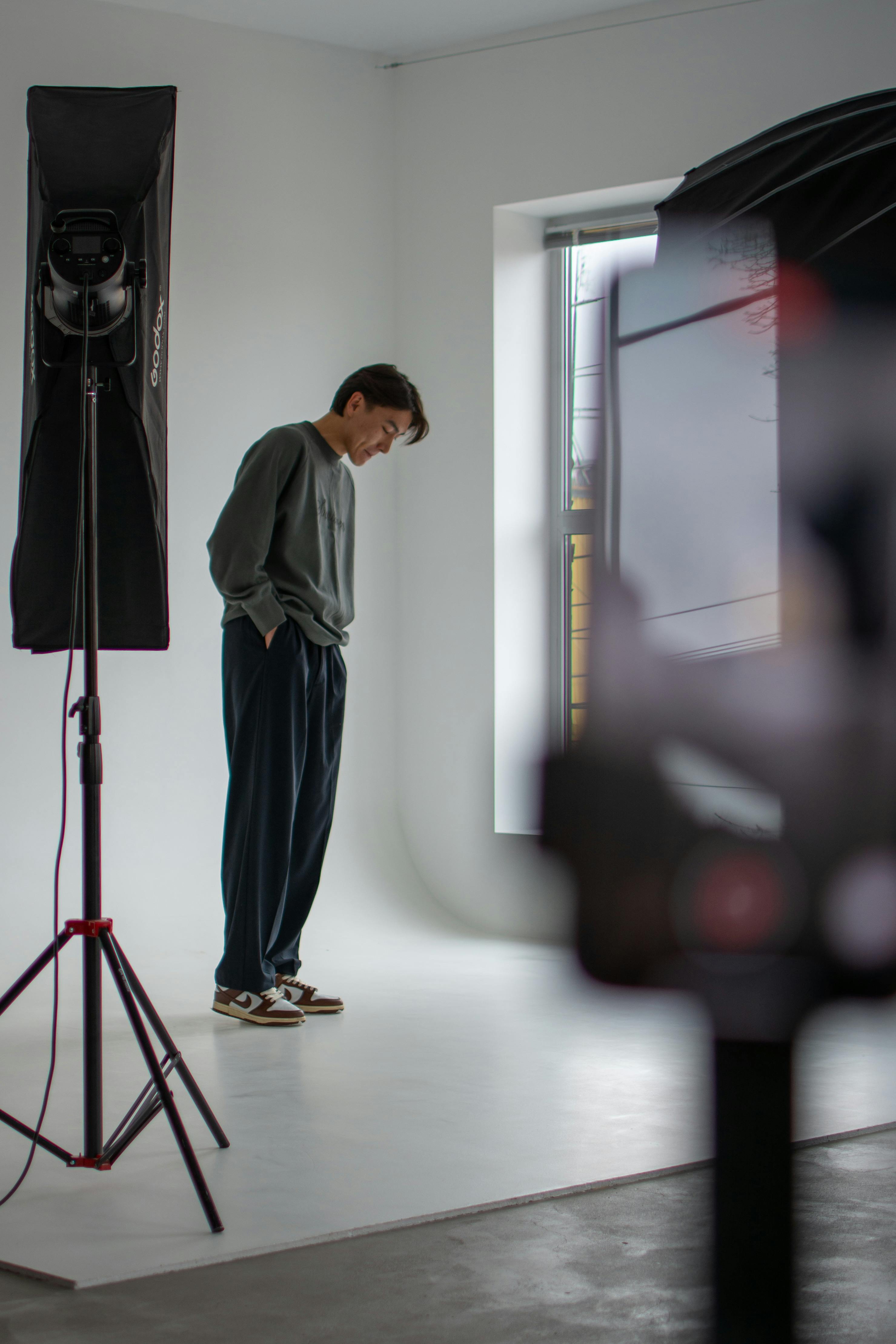 Casually dressed man in a professional studio setting with lighting equipment.