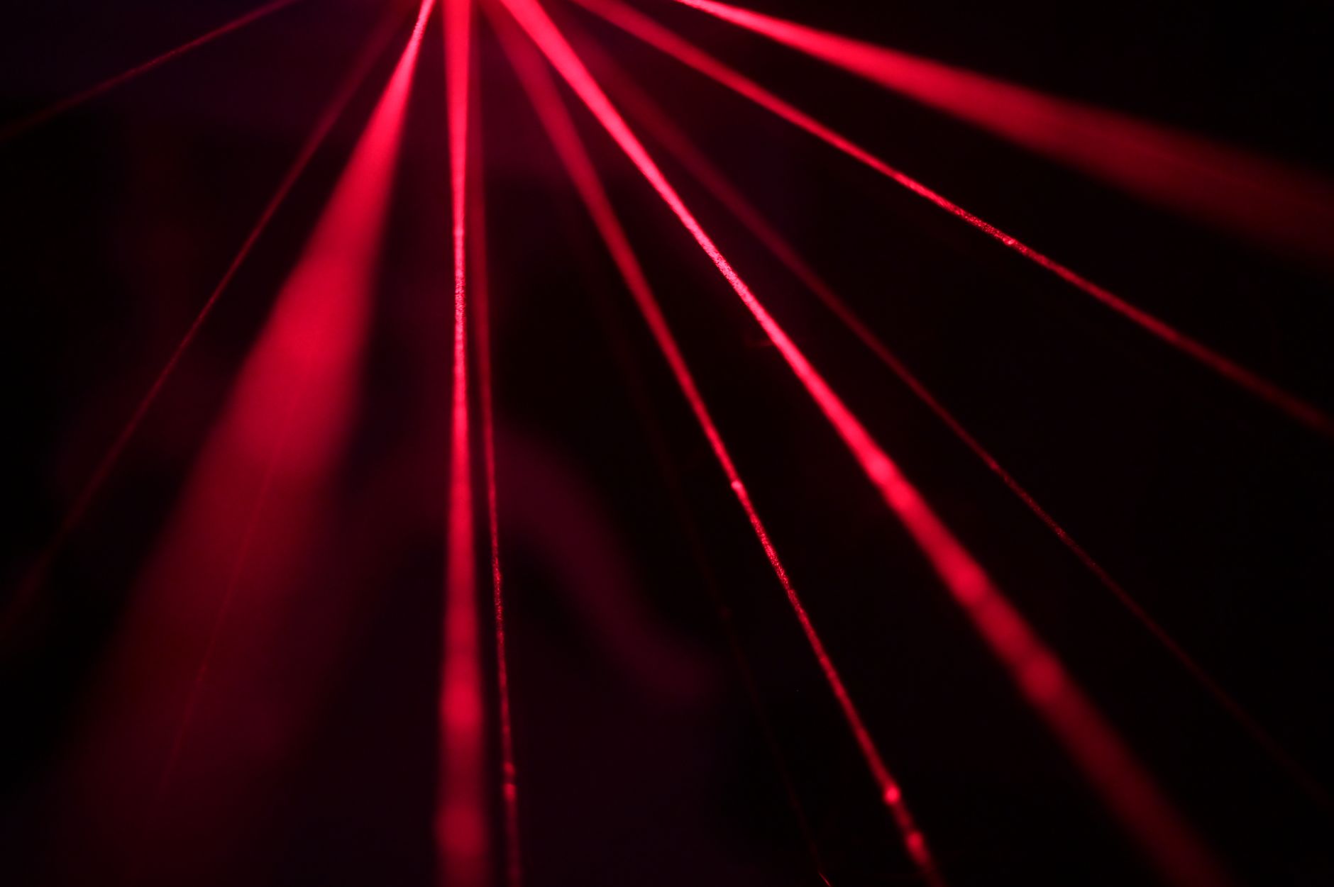 Dynamic red laser beams create a striking abstract pattern in a dark studio setting.